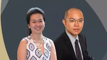 Two individuals smile in front of a geometric backdrop.