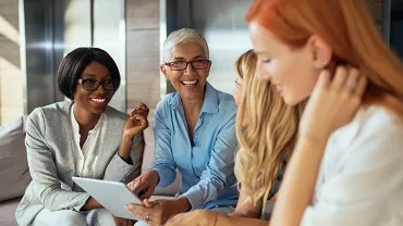 Group of people smiling and looking at a tablet.