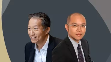 Two people wearing business suits against a dark abstract background.