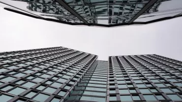Upward view of mirrored glass skyscrapers against a cloudy sky.