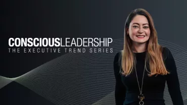 Page Executive Conscious Leadership banner featuring a smiling woman with long blonde hair, wearing a black outfit and a gold necklace, against a dark background with abstract wave patterns.