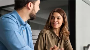 a woman and a man talking in front of the computer