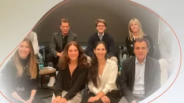 Group of people sitting and standing together in a meeting room.