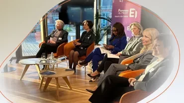 Panel discussion with professionals seated on stage during a corporate event.