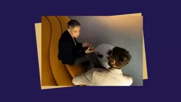 Two professionals having a discussion in a curved seating area.