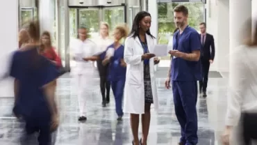 Healthcare professionals reviewing documents in a busy hospital corridor.