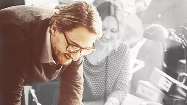 People collaborating at an office desk, discussing a project.