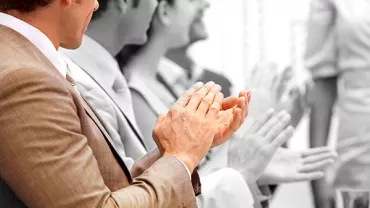 People sitting at a table, applauding.