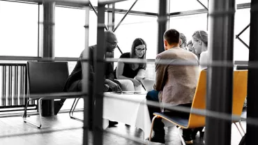 Group of people sitting around a table in a modern office space.