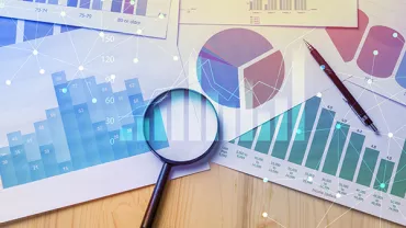 Magnifying glass on business charts and graphs on a desk.