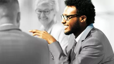 Person in a suit smiling during a meeting.