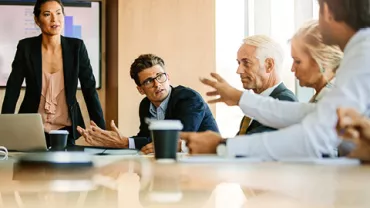 People in a meeting room discussing and gesturing.