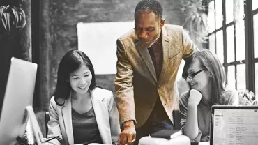 Three colleagues discussing a project around a table.