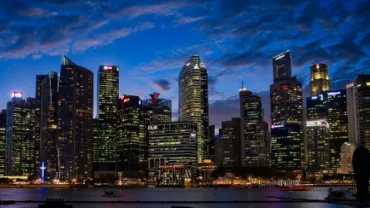 Illuminated city skyline at dusk with skyscrapers by the water