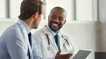 Doctor and colleague discussing while smiling.