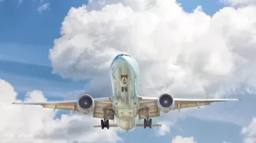 Airplane flying high against a backdrop of fluffy clouds.