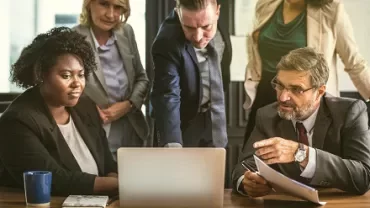 Group of people having a meeting around a laptop in an office.