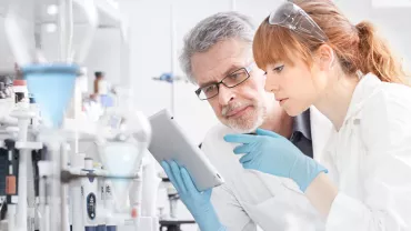 Researchers in a lab examining a tablet.