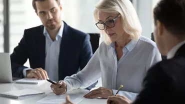 People in a meeting discussing documents at a conference table.