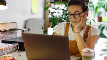 Person working on a laptop in a cozy room with plants.