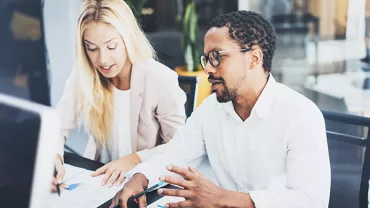 Two people discussing financial documents at a table.