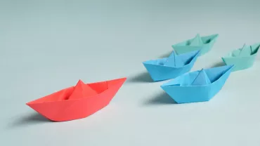 Colorful paper boats on a light blue background.