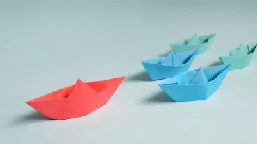 Colorful paper boats on a light blue background.