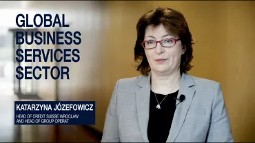 Person in business attire standing indoors, text overlay says 'Global Business Services Sector'.