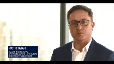 Person in a suit with glasses standing indoors.