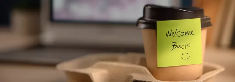 Coffee cup with 'Welcome Back' note and a smiley face.