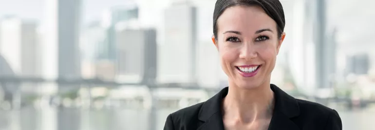 Smiling person in a suit with an urban skyline in the background.