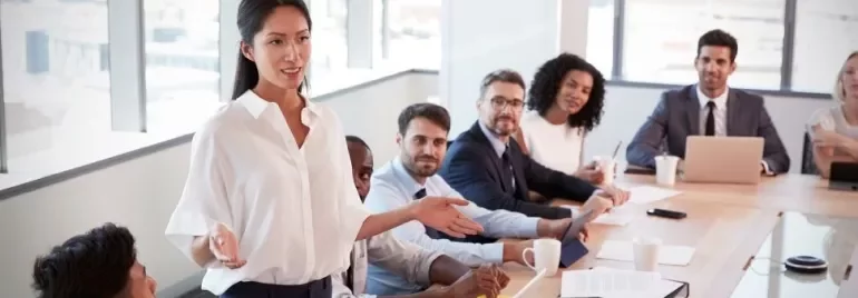 Person leading a meeting with a diverse team around a conference table.