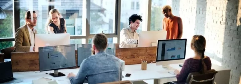 Team collaborating in a bright office with computers.