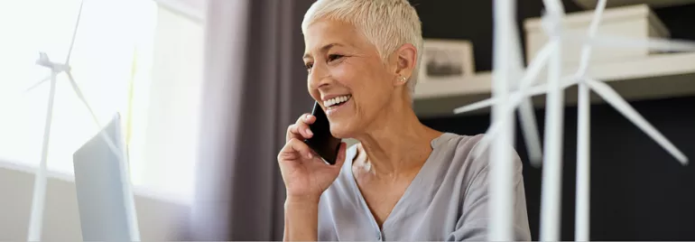 Person smiling and talking on the phone with a wind turbine model nearby.