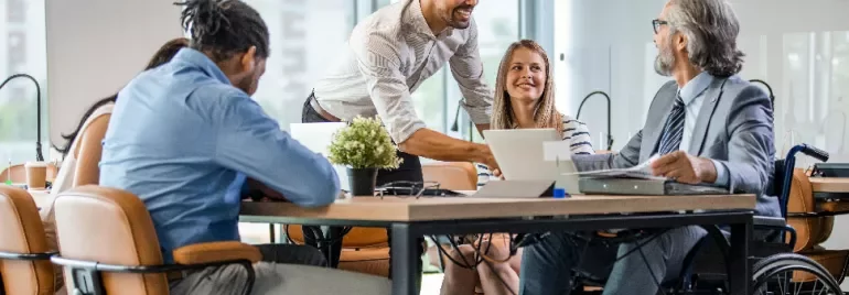 Smiling colleagues in a meeting room discussing around a table.