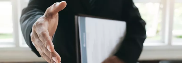 Person in a suit extends a hand for a handshake