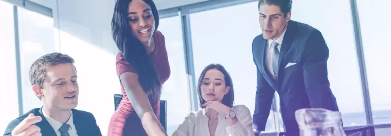 Group of colleagues discussing work around a table in a bright office.