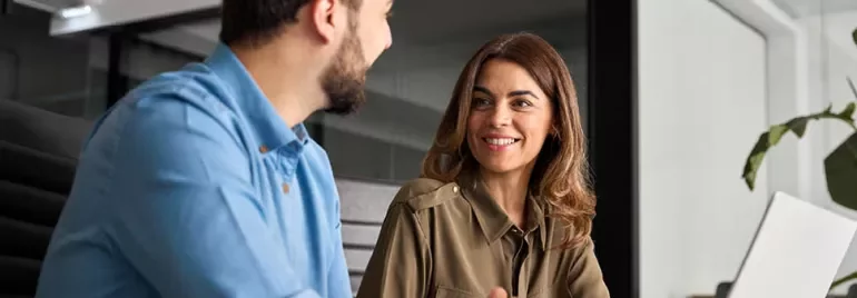 a woman and a man talking in front of the computer