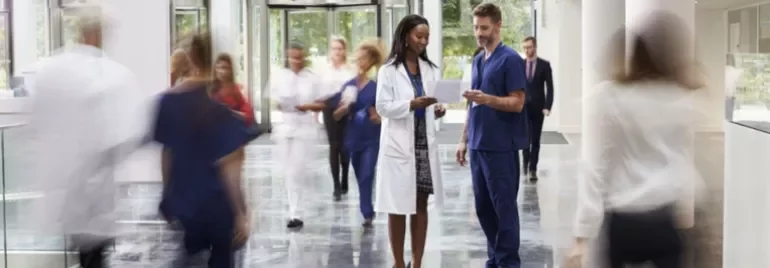 Healthcare professionals reviewing documents in a busy hospital corridor.