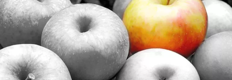 A single colored apple among grayscale apples.