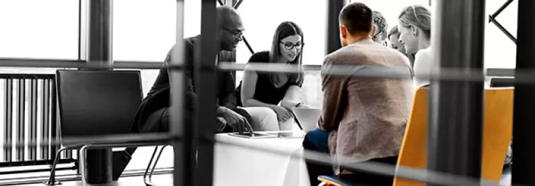 Group of people sitting around a table in a modern office space.