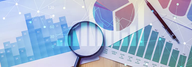 Magnifying glass on business charts and graphs on a desk.