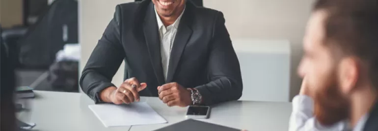 Person in a suit smiling during a meeting at a conference table.