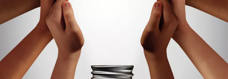 Diverse hands surround a coiled bulb base, symbolizing teamwork and innovation.