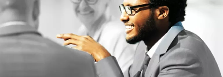 Person in a suit smiling during a meeting.