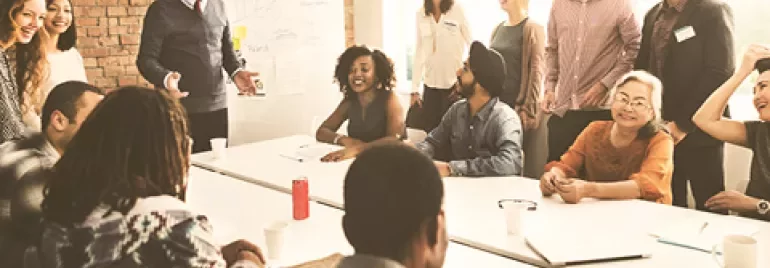 A diverse team having a discussion around a whiteboard in a bright meeting room.