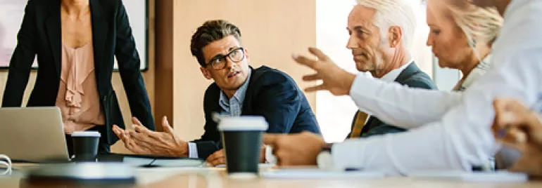 People in a meeting room discussing and gesturing.