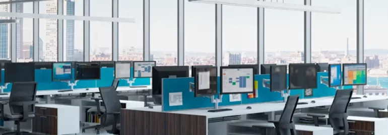 Modern office with large windows and rows of desks with computers.