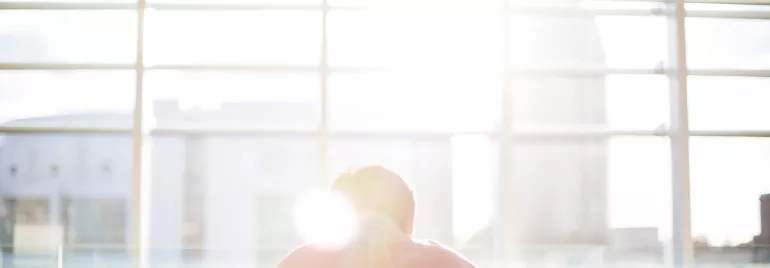 Person sitting at a table with sunlight streaming through a large window.