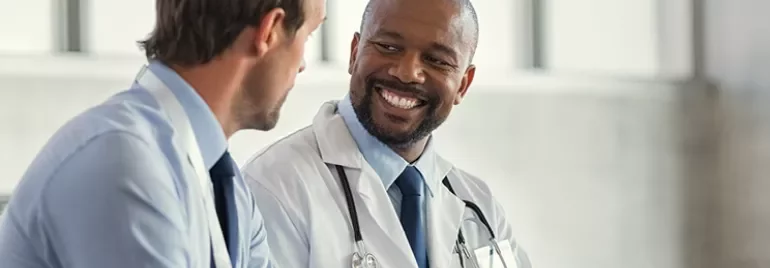 Doctor and colleague discussing while smiling.